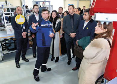 Beschäftigte der neuen Fabrik in Kasachstan führen Gäste der Einweihungsfeier durch das Werk.